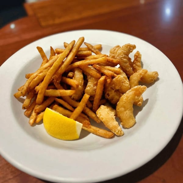 Crispy golden french fries and fried shrimp with a lemon wedge on a white plate.